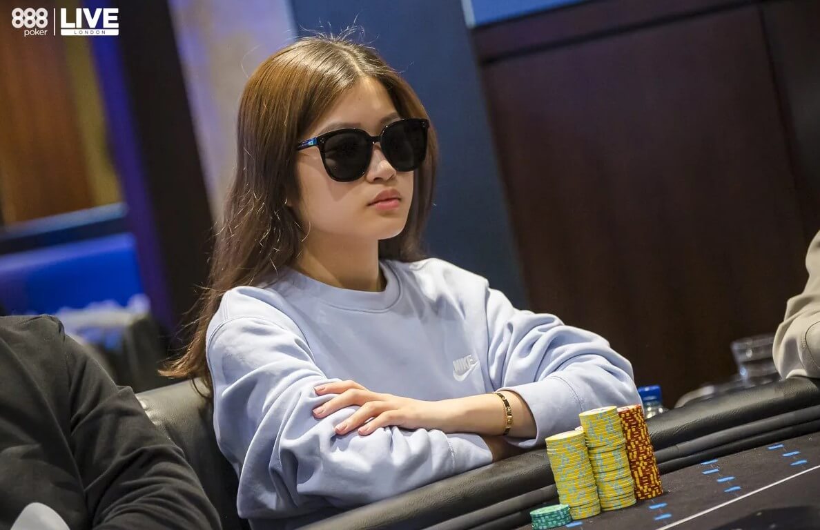 Eine Frau mit Sonnenbrille sitzt an einem Pokertisch